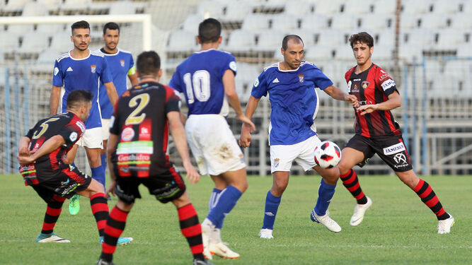 José Vega, rodeado de contrarios y en presencia de su compañero Sergio Narváez, intenta controlar un balón.