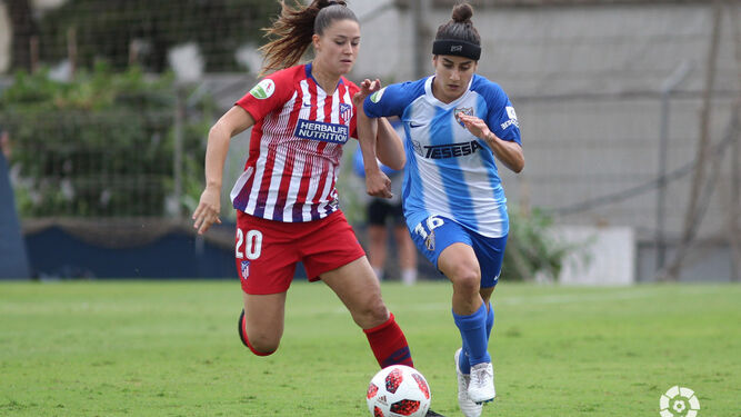 La rojiblanca Viola conduce el balón presionada por la jugadora del Málaga Natalia.