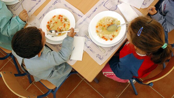 Varios niños almuerzan en un comedor escolar.