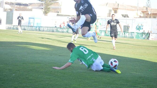 Alberto García se lanza al suelo para cortar el balón y el jugador de la Balona salta para evitar el contacto.