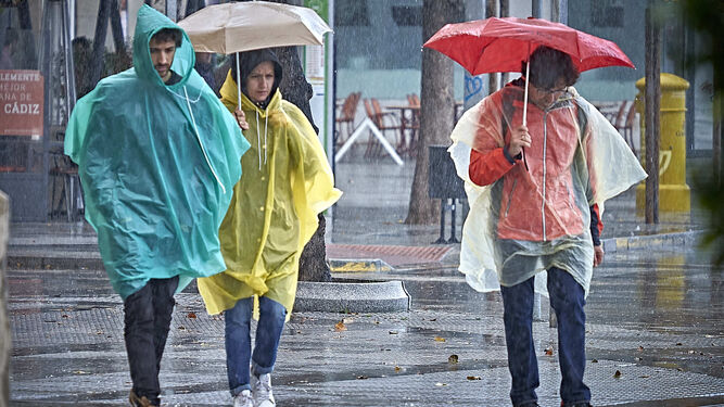 Tres personas se protegen de la lluvia.