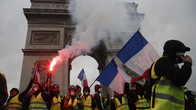 Varios manifestantes pertrechados con chalecos amarillos protestan ayer en el Arco del Triunfo de París.
