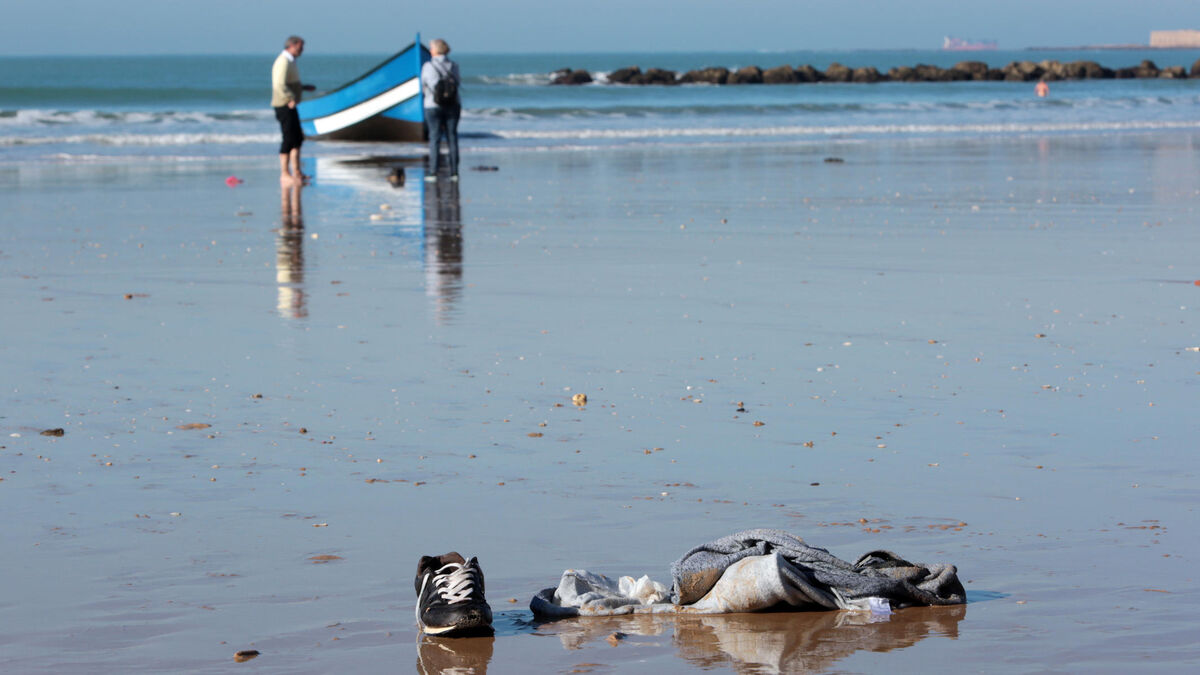 Imagen de la patera en la orilla de la playa Santa María del Mar, con algunas pertenencias en primer plano.