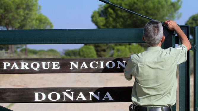 Un guarda forestal cierra una verja del Parque Nacional de Doñana.
