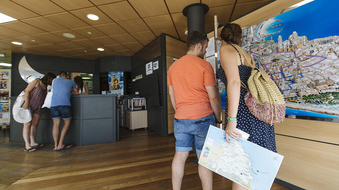 Varios turistas en el interior de la Oficina de Turismo en el paseo de Canalejas.