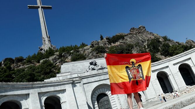 Una persona despliega una bandera anticonstitucional en la explanada del Valle de los Caídos.