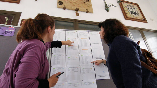 Madres supervisan en un colegio la lista de alumnos solicitantes de plaza.