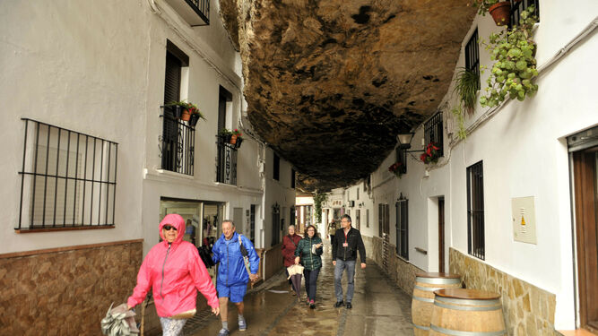 Turistas se refugian de la lluvia en una calle de Setenil.