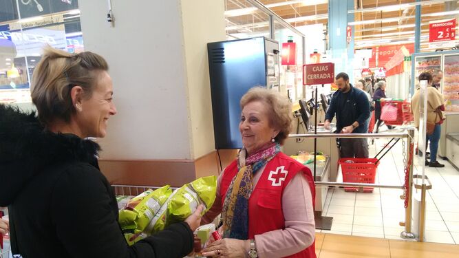 Una clienta de Alcampo entrega alimentos a una voluntaria de Cruz Roja durante la campaña.