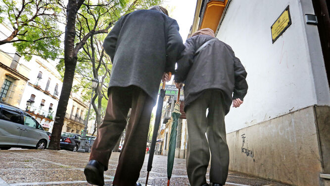 Dos personas mayores caminan por la calle Porvera.