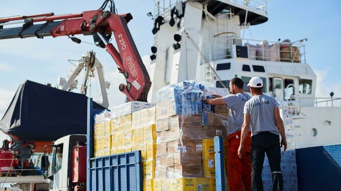 Operarios del 'Open Arms' supervisando este miércoles la carga de ayuda humanitaria al buque tras recibir la autorización para zarpar del puerto de Barcelona, donde lleva bloqueado mas de cien días.