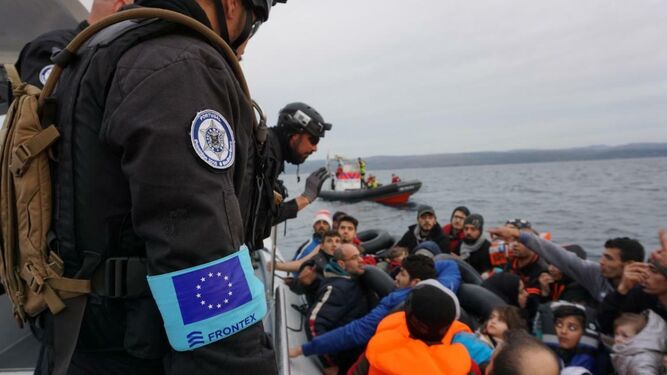 Varios efectivos de Frontex auxilian a un grupo de inmigrantes que navegan en un patera.