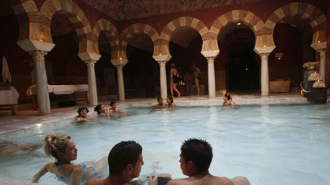 Un grupo de personas se relaja en una de las piscinas de los baños árabes.