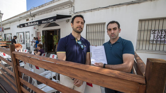 El hostelero Juan Manuel Moreno Visuara y su abogado, Borja Grandall, posan con la demanda presentada contra el Ayuntamiento en la terraza del establecimiento.