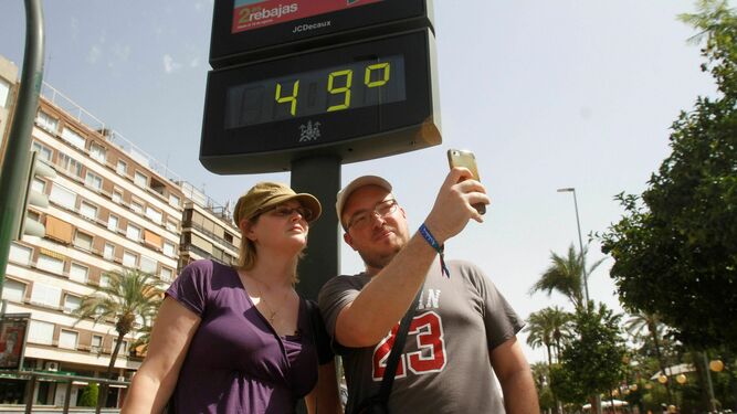 Dos personas se hacen un selfie ante un termómetro.