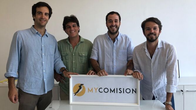 Los socios fundadores de My Comision posan junto al logo de la empresa.