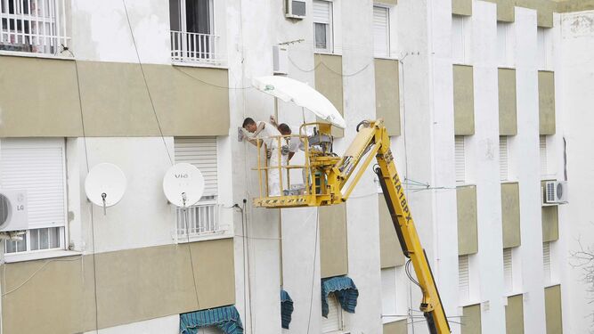 Trabajadores adecentan la fachada de un bloque en la barriada de La Granja.