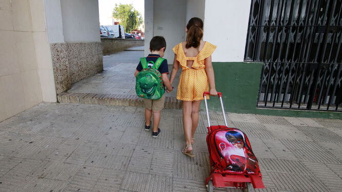 Dos estudiantes, acudiendo a su centro educativo con las mochilas.