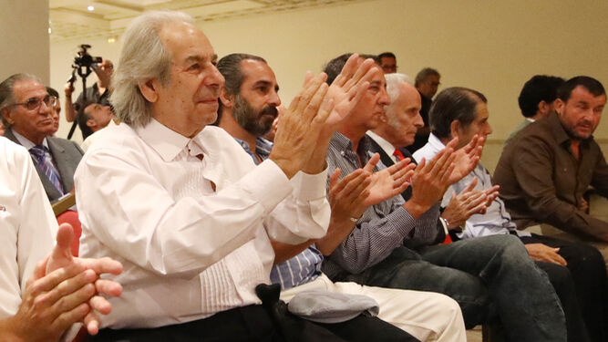 Rafael de Paula, sentado desde el público, aplaude a Manuel Antonio García Paz tras su conferencia.