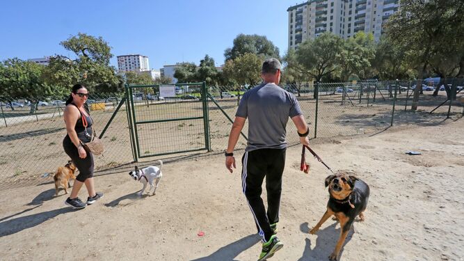 Propietarios de perros paseando  sus mascotas con el parque canino del parque Autóctono cerrado.