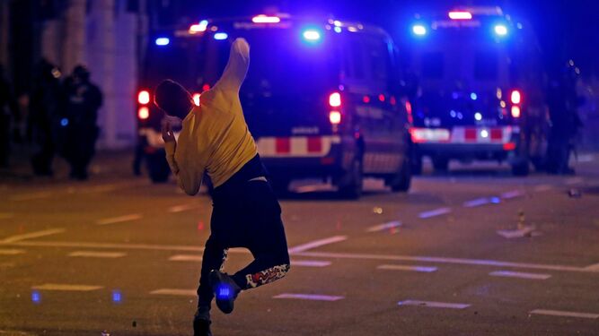 Un manifestante lanza una piedra a los furgones policiales durante los altercados que se han producido este viernes en Girona.