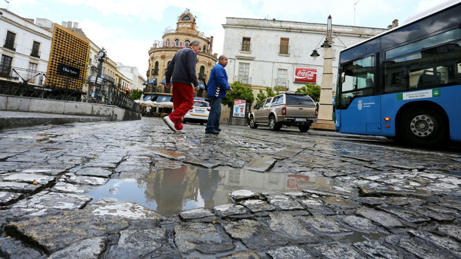 Peatones cruzan por el deteriorado adoquinado junto a la parada de autobús de plaza Esteve.