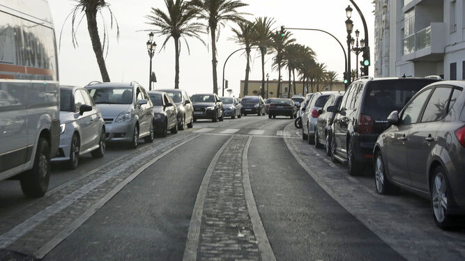Automóviles aparcados y circulando en una calle de la capital gaditana.