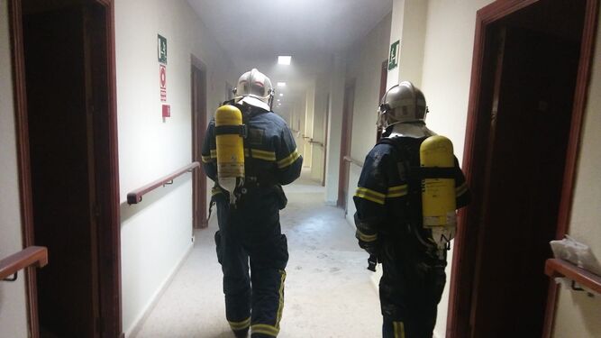 Dos bomberos intervienen en la extinción del incendio en una residencia de ancianos de Medina.