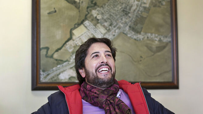 Antonio González en su despacho de alcaldía ante una foto aérea de cómo era el pueblo el año de su independencia.