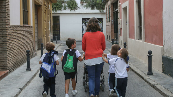 Una mujer con cinco niños pasea por una calle de Sevilla.