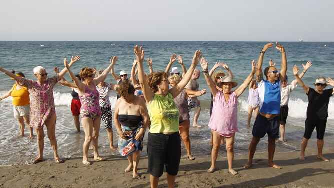 Personas mayores realizando ejercicio físico en la playa.