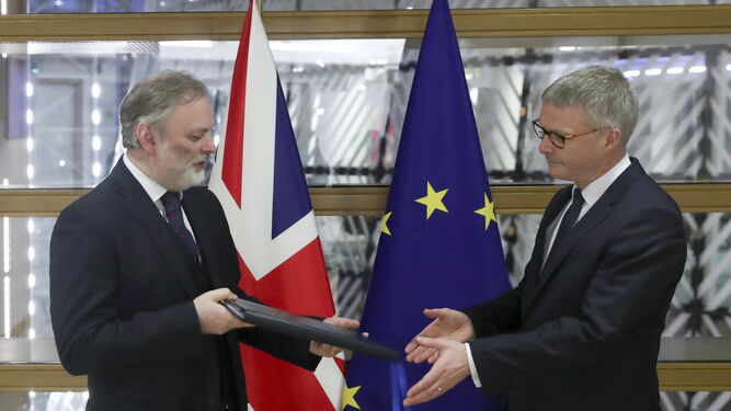 El representante británico ante la UE, Tim Barrow (izq.), entrega el documento que ratifica el 'Brexit' al secretario del Consejo Europeo, Jeeppe Tranholm-Mikkelsen.
