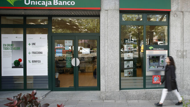 Una mujer pasa por delante de una oficina de Unicaja Banco.