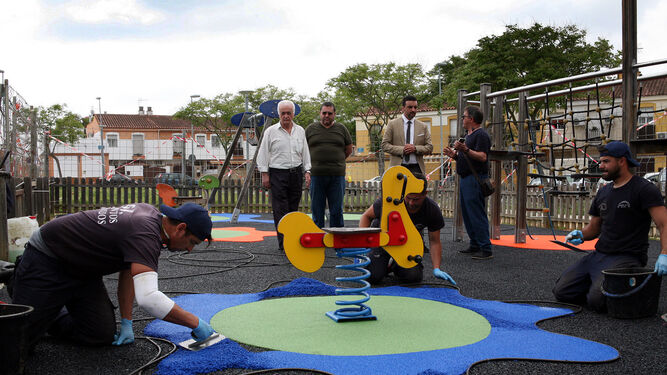 Un trabajador instala suelo de caucho en un parque infantil.