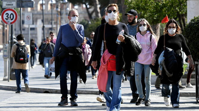 Un grupo de turistas protegiéndose con mascarillas por las calles de Roma.