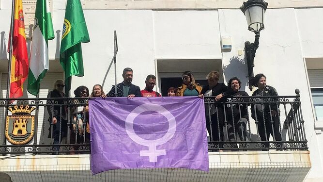El alcalde y representantes de colectivos de mujeres han colocado una bandera conmemorativa en la Plaza de España.