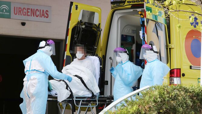 Sanitarios debidamente protegidos bajando de la ambulancia a un paciente considerado como caso sospechoso este jueves en las Urgencias de Jerez.