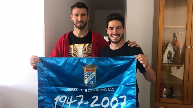 Fran Sabaté y Jose Ortega posan en su casa con la bandera del Xerez CD.