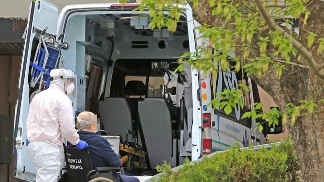 Un profesional baja a un paciente de la ambulancia en el hospital de Jerez.