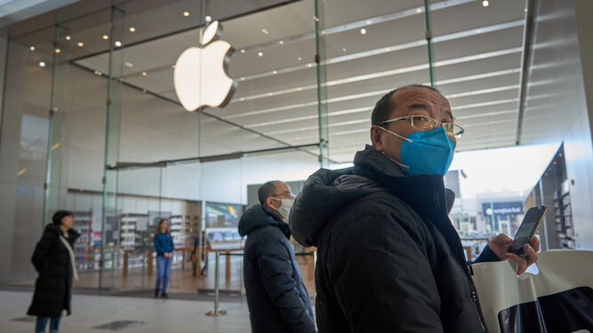 Una persona pasea con una mascarilla cerca de una tienda Apple.