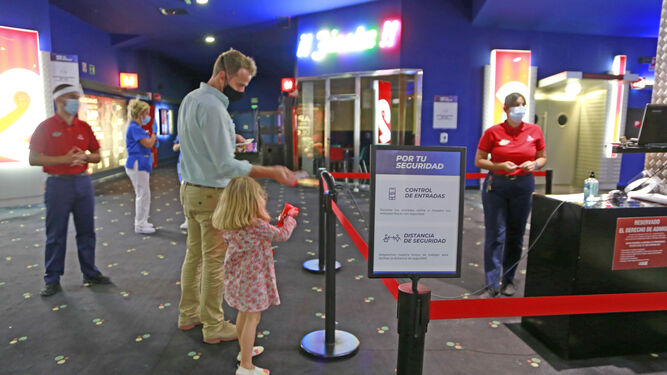 Un padre y su hija acceden a los cines con la entrada electrónica, en la tarde de este viernes.