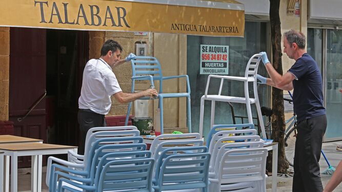 Camareros limpian las sillas de los veladores de un bar del centro.