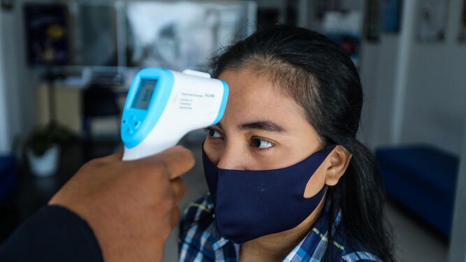 Toman la temperatura a una mujer indonesia para evitar la diseminación del coronavirus.
