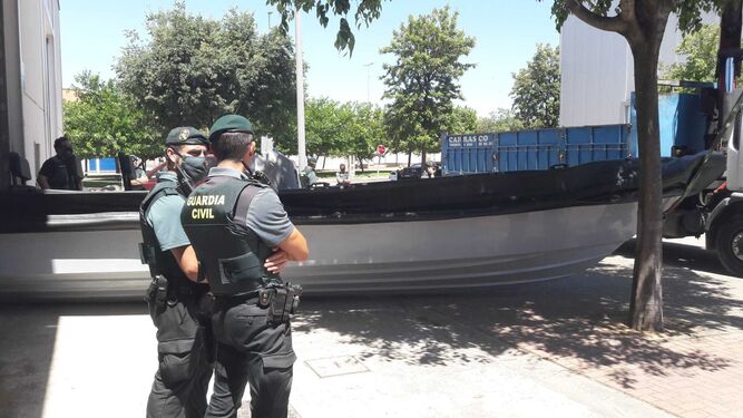 Agentes de la Guardia Civil, ante la narcolancha en Jerez, antes de ser llevada con una grúa a un camión.