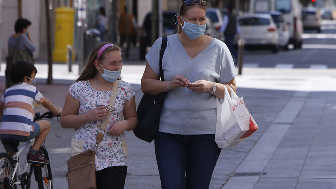 Una madre y su hija, por una calle de Sevilla, con mascarilla.