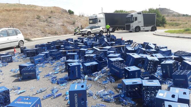 Las cajas de plástico con botellas de cristal, tras el accidente en la rotonda de la Cartuja con la autopista.
