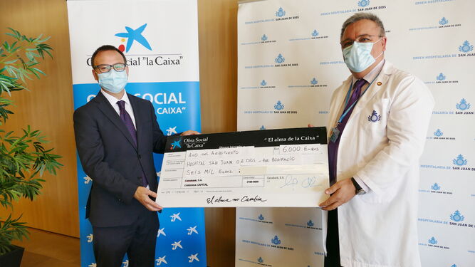 Javier Aznar, de Caixabank, entrega la donación al responsable del Hospital San Juan de Dios.