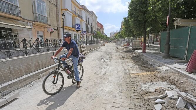 Un hombre circula con una bicicleta por la calle Corredera.