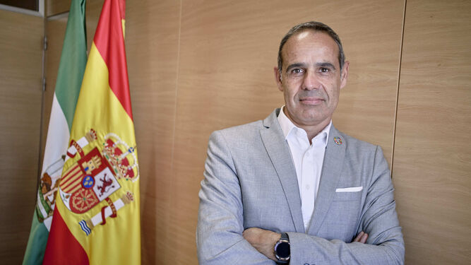 José Pacheco posando ante las banderas de España y Andalucía en su despacho.