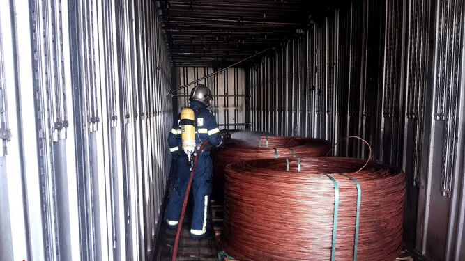Un bombero enfría una de las bobinas de cobre que transportaba el camión siniestrado.